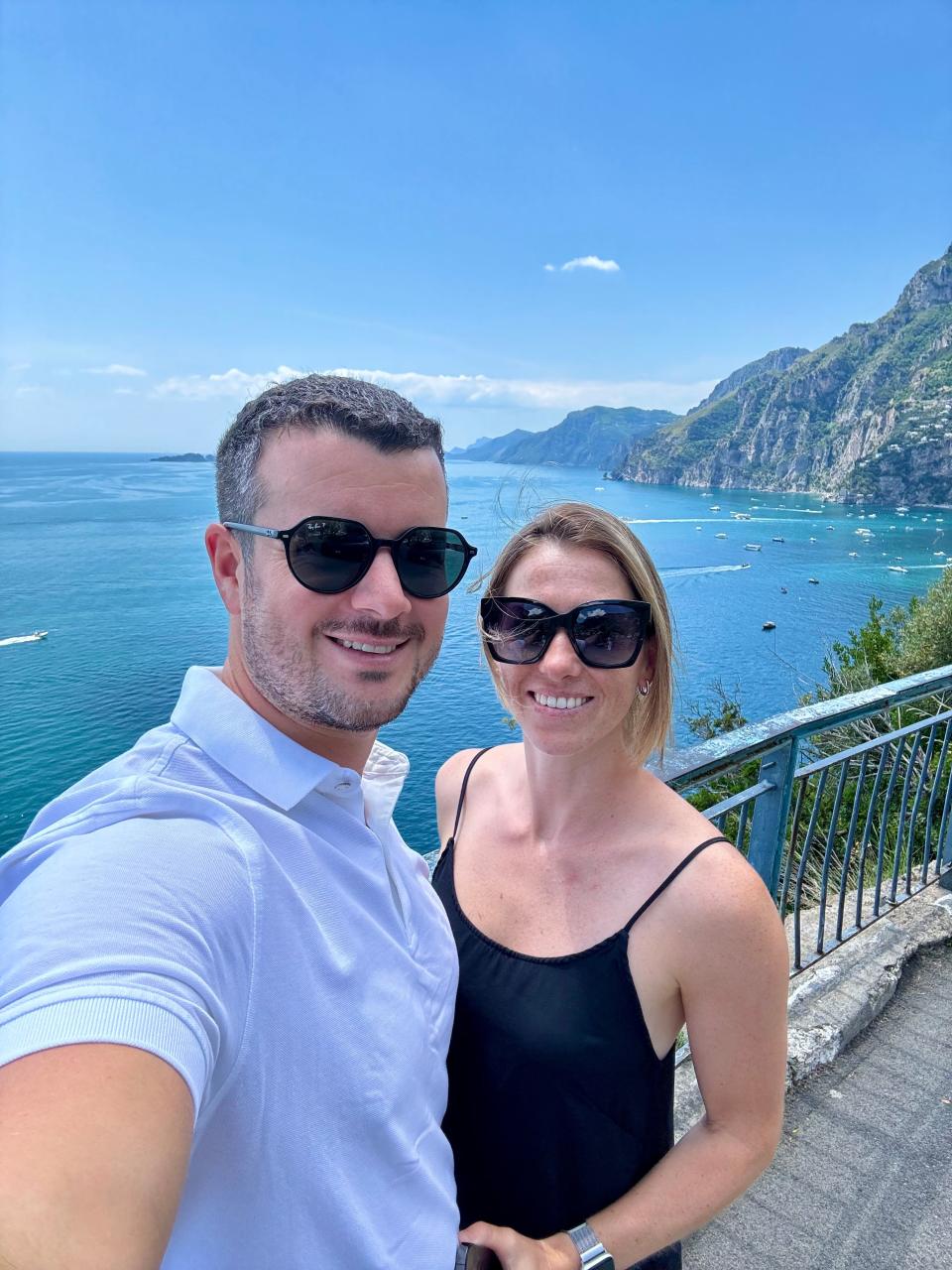 Lucas Frischmann and his wife posing in front of a scenic ocean view.