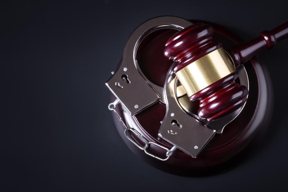 Wooden judge gavel and police handcuffs isolated on black background