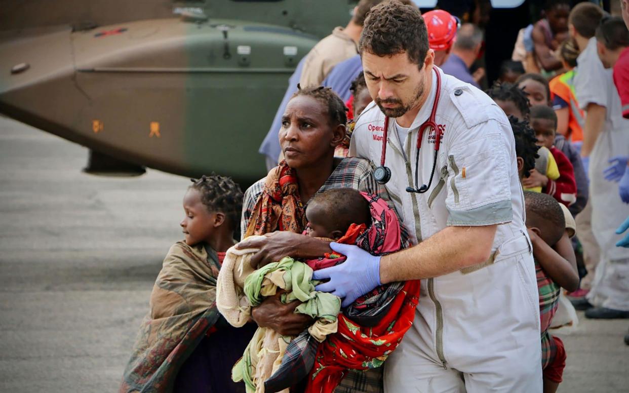 Aid workers escort people to safety at the airport of the coastal city of Beira in central Mozambique - AFP