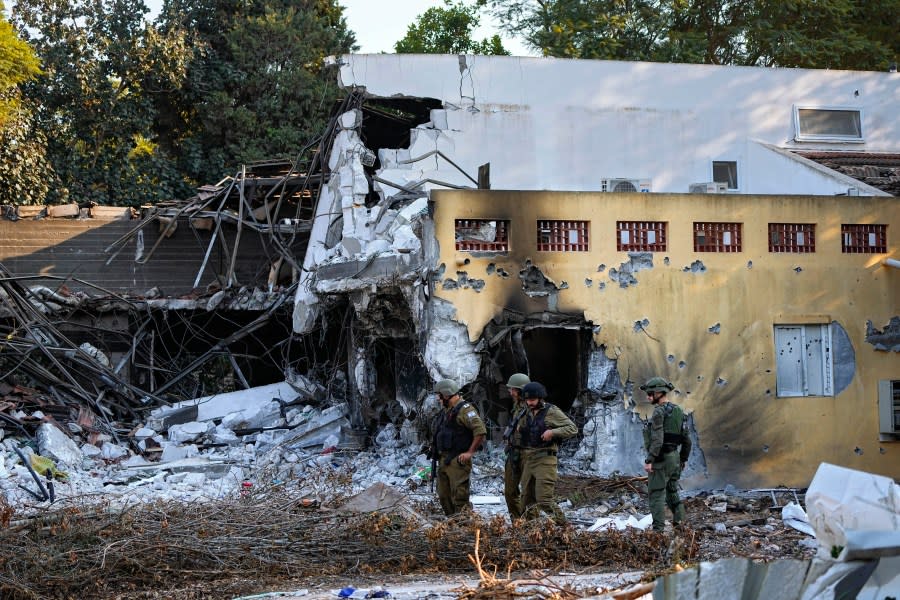 Israeli soldiers walk past houses destroyed by Hamas militants in Kibbutz Be'eri, Israel, Saturday, Oct. 14, 2023. The kibbutz was overrun by Hamas militants from the nearby Gaza Strip on Cot.7, when they killed and captured many Israelis. (AP Photo/Ariel Schalit)