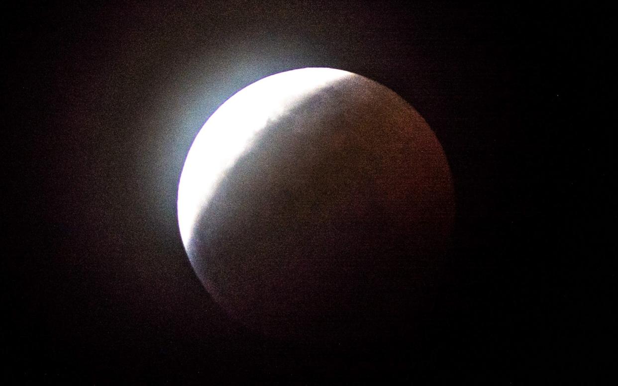 Earth's shadow begins to totally obscure the view of the so-called Super Blood Wolf Moon during a total lunar eclipse - AFP