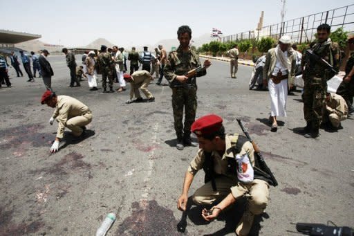 Yemeni military police collect evidence at the site of a suicide bomb attack in Sanaa on Monday. Yemen's military has cancelled a parade planned for Tuesday to mark the reunification of the country after nearly 100 soldiers were killed in a massive suicide attack claimed by Al-Qaeda, an official said