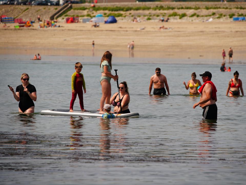 People on a paddleboard in the sea in St Michael's Bay in Cornwall (PA)