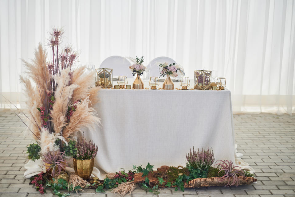 A beautifully decorated wedding sweetheart table with elegant floral arrangements, gold accents, and nature-inspired details
