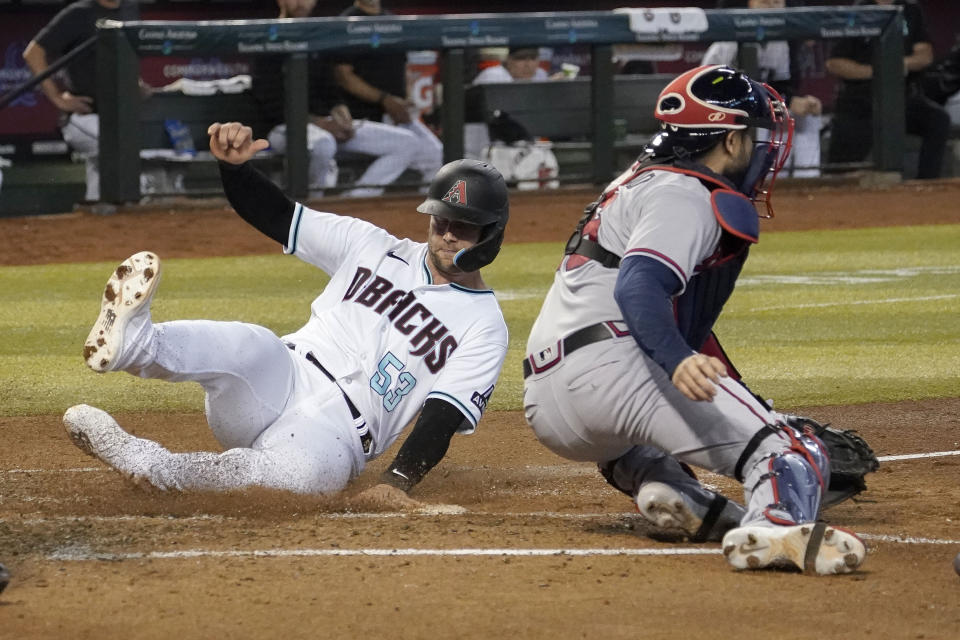 Arizona Diamondbacks' Christian Walker touches home plate safely past Atlanta Braves catcher Travis d'Arnaud during the third inning of a baseball game, Sunday, June 4, 2023, in Phoenix. (AP Photo/Darryl Webb)