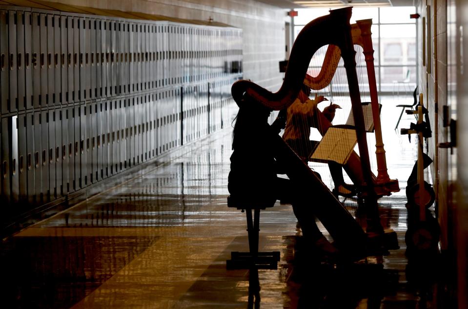 Cass Technical High School students Sydni Byrd, 18 and Bre'yona Dowe 16, practice on the harp in the hallway outside of Lydia Cleaver's class on Friday, March 24, 2023. The harp program at the high school is closing in celebrating its centennial year.