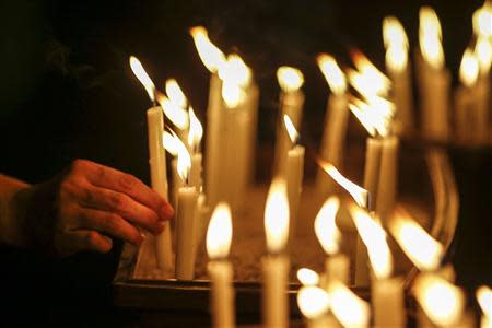 A woman places a candle after a candlelight vigil for the passengers of the missing Malaysia Airlines MH370 in central Kuala Lumpur March 27, 2014. REUTERS/Athit Perawongmetha