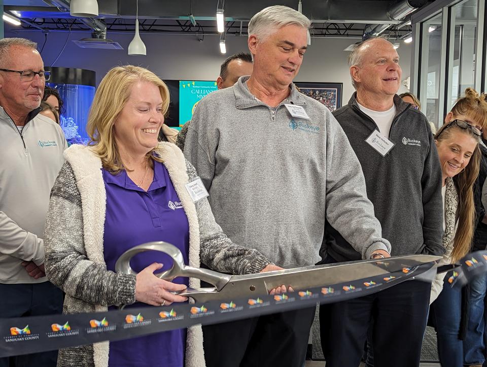 Buckeye Community School CEO Mary Snell holds the scissors for the Chamber of Commerce ribbon cutting for the new school. To her right, Chief Operating Officer Pete Bartkowiak explains details about the school to chamber members.