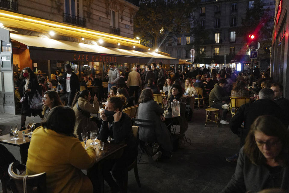 Parisians take a drink on the terrace of a restaurant before the nightly curfew due to the restrictions against the spread of coronavirus, in Paris, France, Friday, Oct. 23, 2020. (AP Photo/Francois Mori)