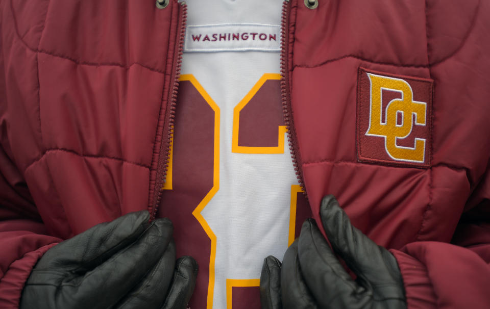 Washington NFL jersey shows just "Washington" with a red jacket worn over the top with the logo replaced with a gold "DC" emblem.