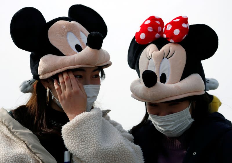 Visitors wearing protective face masks and Mickey and Minnie Mouse costumes, following an outbreak of the coronavirus, are seen outside Tokyo Disneyland in Urayasu