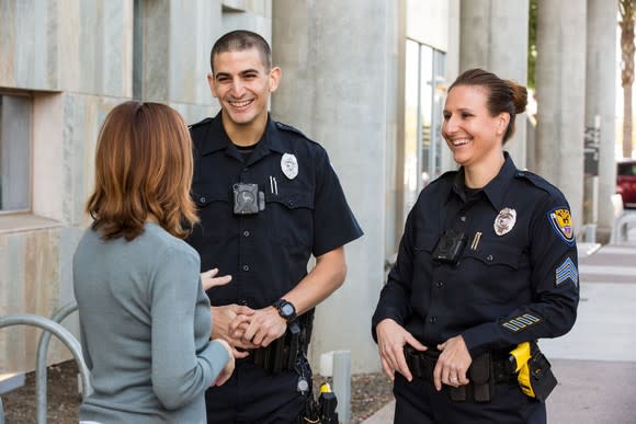 Police officers waring body cameras & talking with citizens.