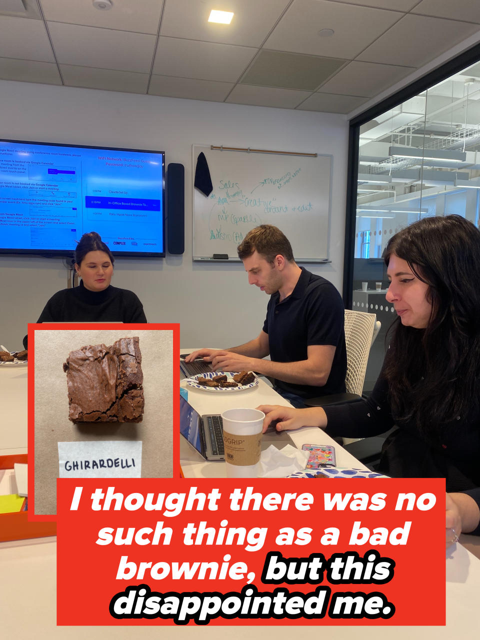 Three colleagues are in a meeting with laptops, a whiteboard in the background, and snack remnants on the table