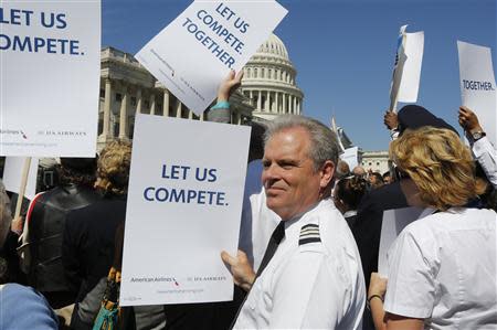 US Airways 777 pilot Rob Ingram, based in Dallas, holds a sign as pilots, flight attendants, baggage handlers and other union members working for American Airlines and US Airways demonstrate urging the U.S. Justice Department to allow the two companies to merge at a rally in front of the U.S. Capitol building in Washington September 18, 2013. REUTERS/Jim Bourg