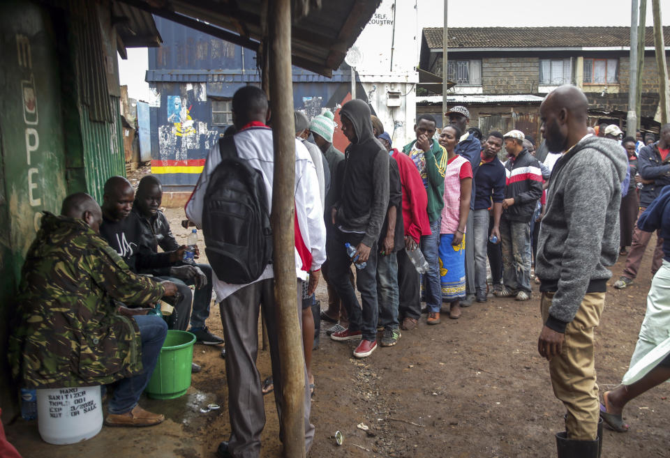 Kenianos se forman para recibir desinfectante del gobierno en botellas de plástico que ellos llevan para intentar contener la propagación del nuevo coronavirus en el barrio Toi Market en Nairobi, Kenia, el sábado 28 de marzo de 2020. (AP Foto/Brian Inganga)