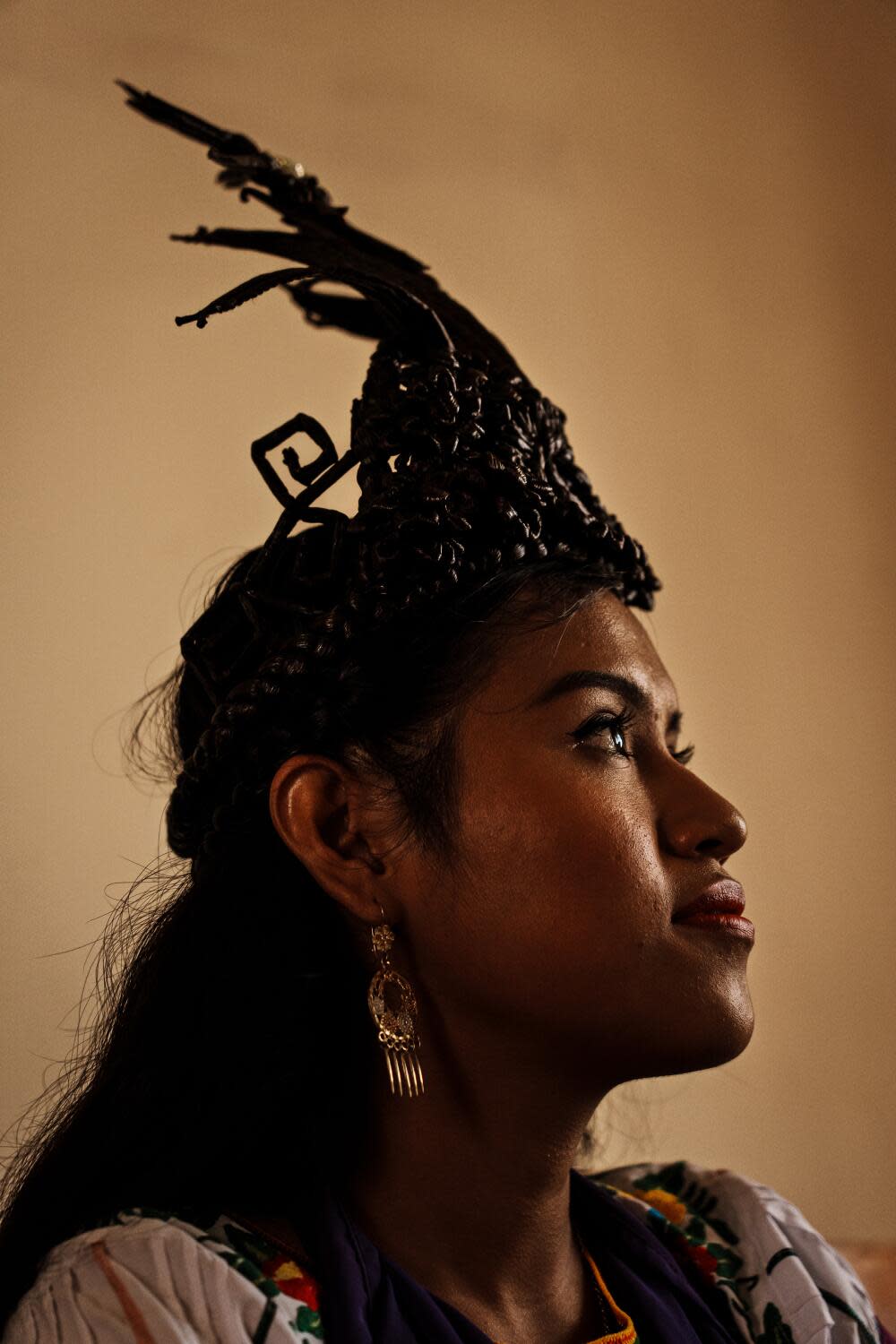 A woman with dark hair wearing a dark headdress, looking to the side