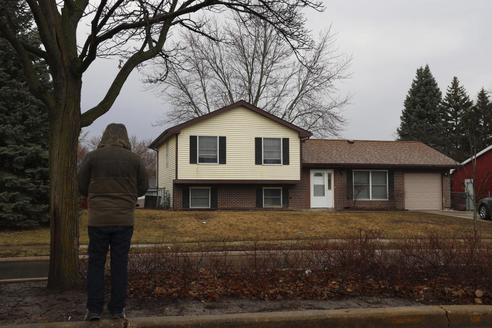 A man stands and looks at the home in Bolingbrook, Ill., on Monday, March 6, 2023, where three people were fatally shot, and another person was wounded Sunday night. Prosecutors said a 17-year-old has been charged with multiple counts of first-degree murder and other crimes in the fatal shootings of a girl he was dating and two other people in suburban Chicago. (Stacey Wescott/Chicago Tribune via AP)