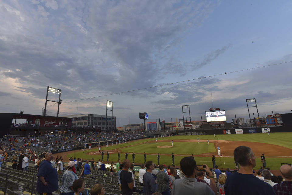 FILE - Players stand during the national anthem before the Rosemont Dogs played their baseball home-opener against the Milwaukee Milkmen at Impact Field in Rosemont, Ill., in this Tuesday, July 7, 2020, file photo. Minor league teams across the country are set to open their seasons Tuesday, May 4, 2021, returning baseball to communities denied the old national pastime during the coronavirus pandemic. (John Starks/Daily Herald, via AP, File)