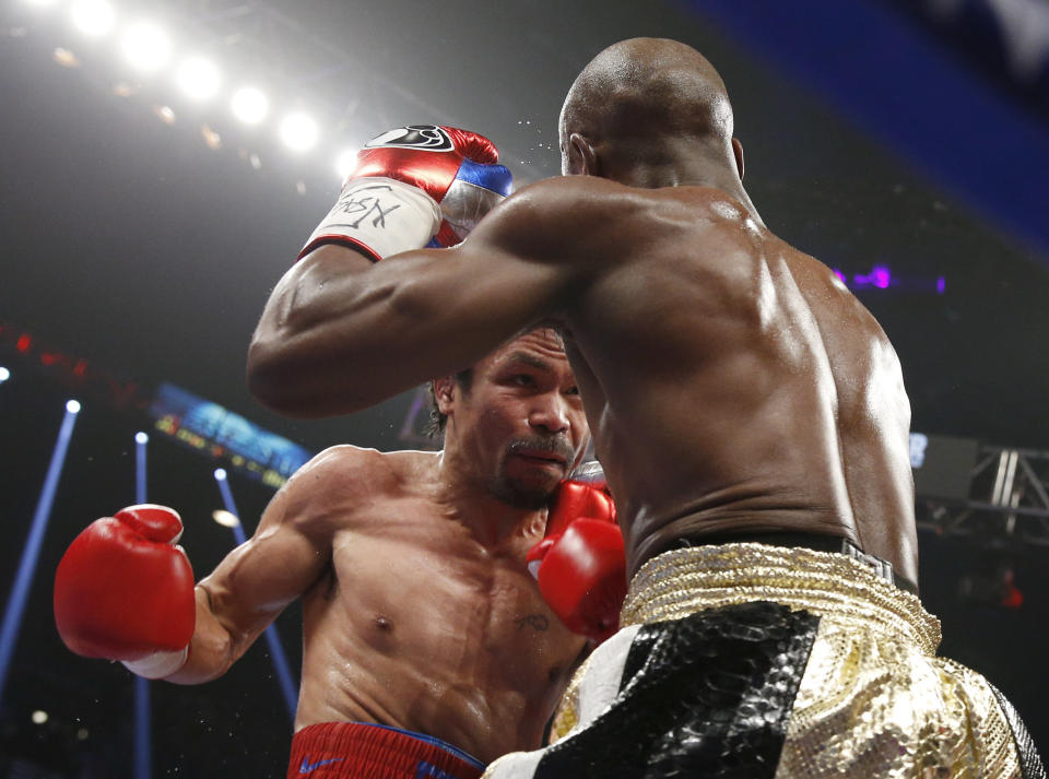 Manny Pacquiao, left, from the Philippines, trades blows with Floyd Mayweather Jr., during their welterweight title fight on Saturday, May 2, 2015 in Las Vegas. (AP Photo/John Locher)