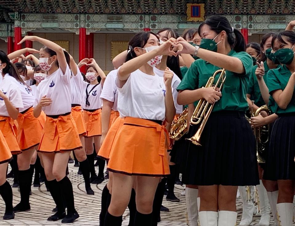 ▲橘高校吹奏樂部與北一女樂儀旗隊學生一起比愛心拍照，互動溫馨可愛。