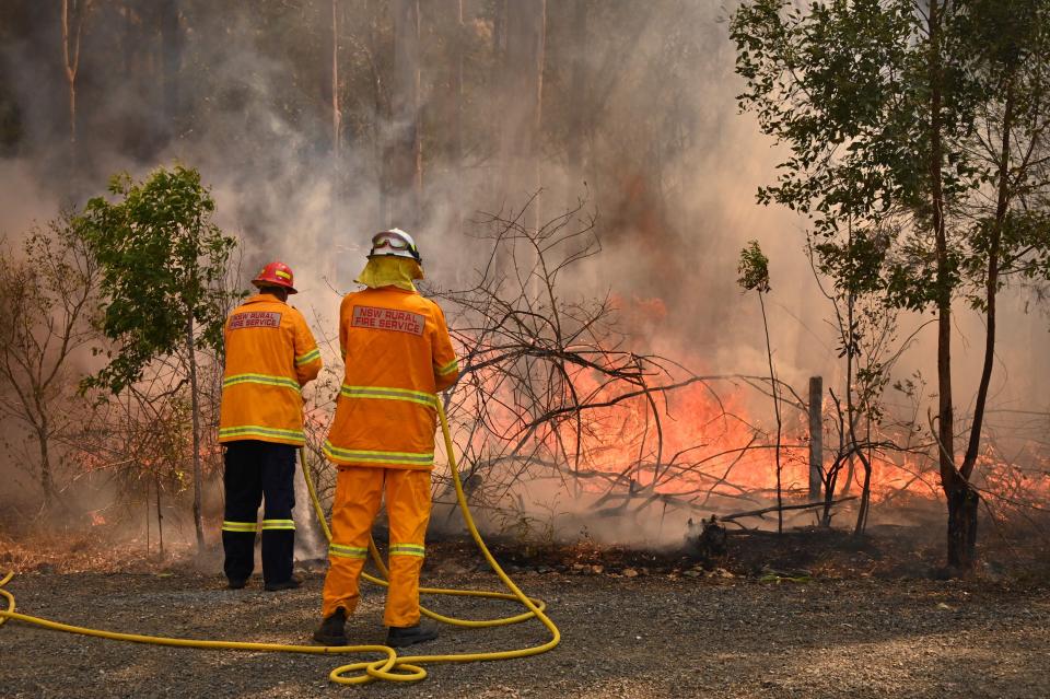 Firefighters tackle a bushfire to save a home in Taree, north of Sydney, on Saturday. (Photo: PETER PARKS/AFP via Getty Images)