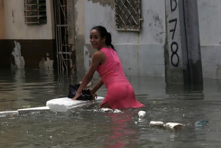 A woman keeps her shoes dry on a piece of foam board while wading through a flooded street, after the passing of Hurricane Irma, in Havana, Cuba September 10, 2017. REUTERS/Stringer