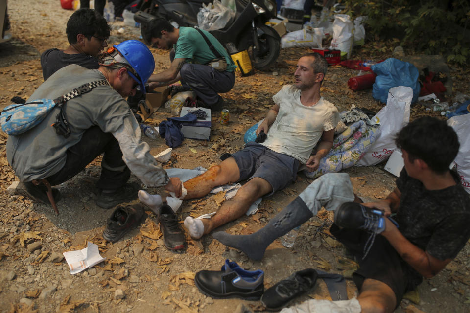 Turkish volunteers rest as they fight wildfires in Turgut village, near tourist resort of Marmaris, Mugla, Turkey, Wednesday, Aug. 4, 2021. Hundreds of volunteers have joined efforts to contain blazes that have swept through forests in Turkey's southern and southwestern coasts, fueled by a summer heatwave, low humidity and strong winds. The fires, described as Turkey's worst in living memory, have so far killed eight people _ including a teenaged volunteer who was carrying drinking water and other refreshments to firefighters in Marmaris. (AP Photo/Emre Tazegul)