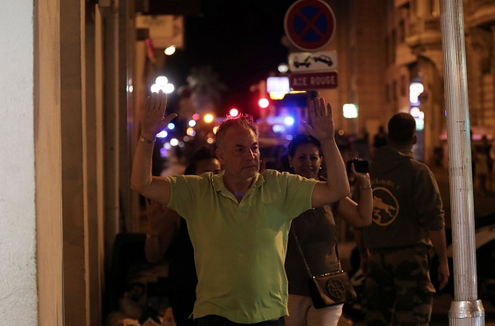 A man walks with his hands up as police officers carry out checks on people in Nice following an attack. Photo: Getty