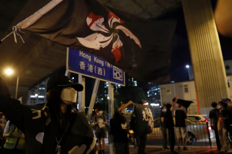 Woman waves a black Hong Kong flag during a candlelight vigil ahead of the 31st anniversary of the crackdown of pro-democracy protests at Beijing's Tiananmen Square in 1989, in Hong Kong