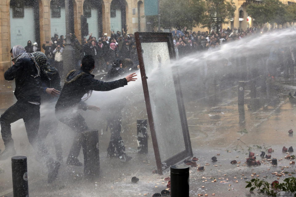 Riot police use a water cannon against anti-government demonstrators at a road leading to the parliament building in Beirut, Lebanon, Saturday, Jan. 18, 2020. Riot police fired tears gas and sprayed protesters with water cannons near parliament building to disperse thousands of people after riots broke out during a march against the ruling elite amid a severe economic crisis. (AP Photo/Hassan Ammar)