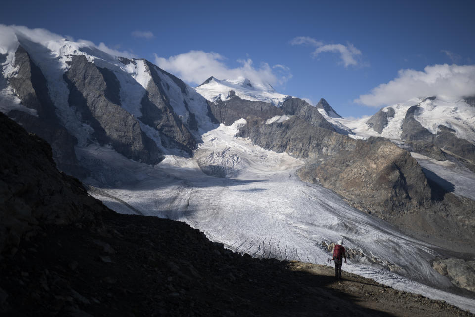 A person stands in front of the Bernina mountain group with the Pers and Morteratsch glaciers in Pontresina, Switzerland, Wednesday, August 10, 2022. (Gian Ehrenzeller/Keystone via AP)