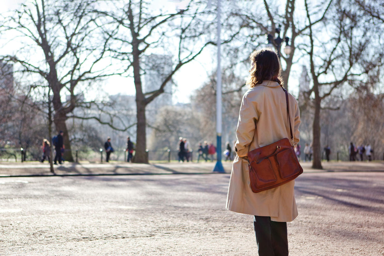 Woman in a trench coat looking on at a park Getty Images/James Whitaker