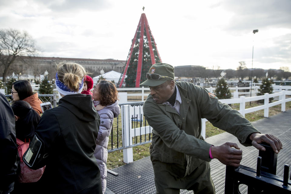 A National Park Service employee closes the gate to visitors at the National Christmas Tree on the Ellipse near the White House, Monday, Dec. 24, 2018, in Washington. The area was reopened after electrical repairs were made. These repairs were delayed because of the partial government shutdown. Both sides in the long-running fight over funding President Donald Trump's U.S.-Mexico border wall appear to have moved toward each other, but a shutdown of one-fourth of the federal government entered Christmas without a clear resolution in sight. (AP Photo/Andrew Harnik)