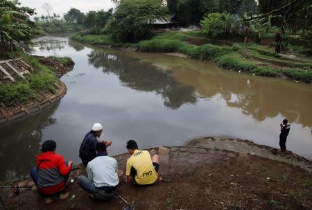 Men fish at a polluted tributary, which runs through an area densely populated with textile factories and where it joins the Citarum river, near Majalaya, south-east of Bandung, West Java province, Indonesia, February 14, 2018. REUTERS/Darren Whiteside