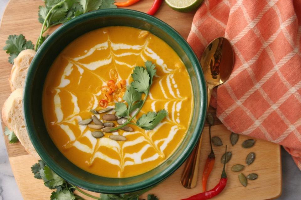 Bowl of Instant Pot pumpkin soup with garnish and tableware.