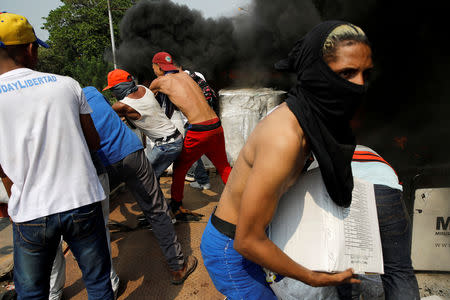 Opposition supporters unload humanitarian aid from a truck that was set on fire after clashes between opposition supporters and Venezuela's security forces at Francisco de Paula Santander bridge on the border line between Colombia and Venezuela as seen from Cucuta, Colombia, February 23, 2019. REUTERS/Marco Bello TPX IMAGES OF THE DAY