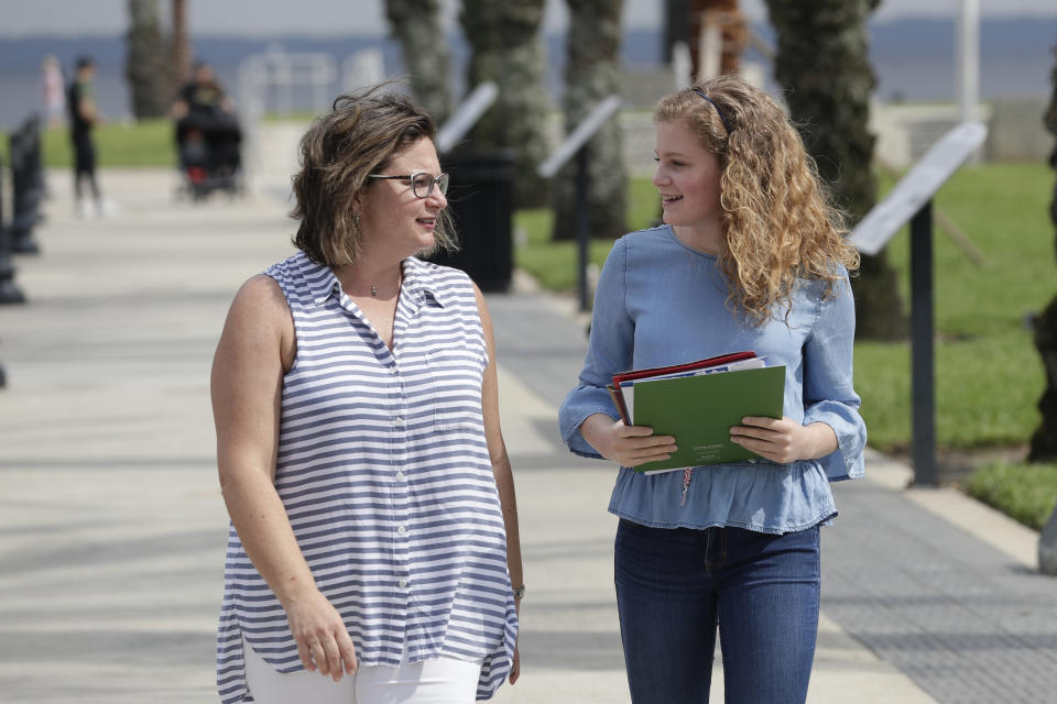 In this Friday, April 10, 2020 photo, Ebru Ural, left, and her daughter Serra Sowers take a walk to discuss choosing colleges without actually visiting them at a park in Sanford, Fla. The coronavirus pandemic has changed the process of college visits to virtual interviews and visits. (AP Photo/John Raoux)