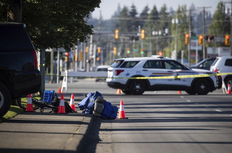 A bike and person's belongings are seen on the sidewalk behind police tape at the scene of a shooting in Langley, British Columbia, Monday, July 25, 2022. Canadian police reported multiple shootings of homeless people Monday in a Vancouver suburb and said a suspect was in custody. (Darryl Dyck/The Canadian Press via AP)