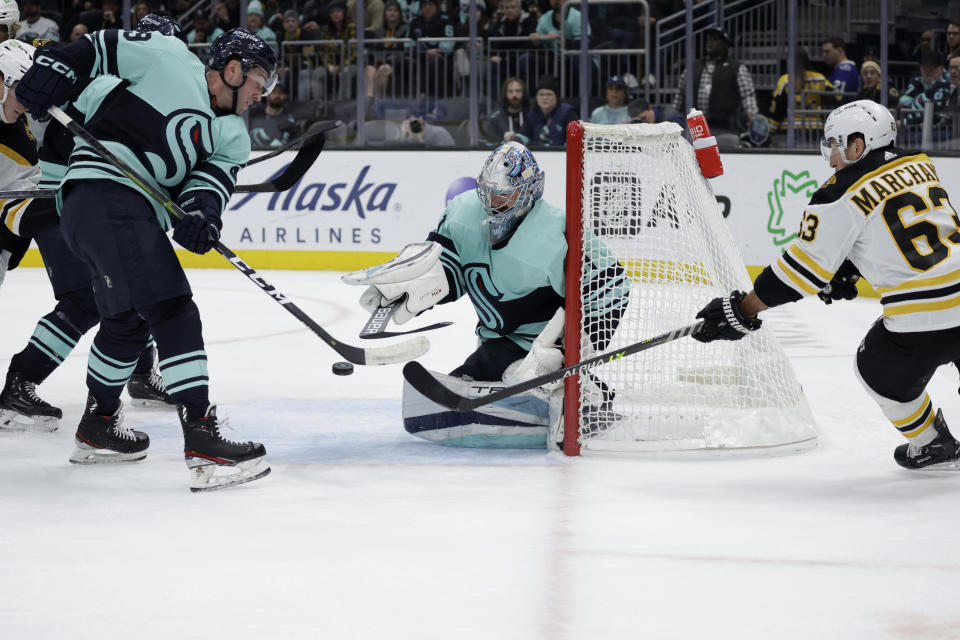Boston Bruins left wing Brad Marchand (63) puts the puck in front of the goal as Seattle Kraken goaltender Philipp Grubauer (31) and defenseman Vince Dunn (29) defend during the first period of an NHL hockey game Thursday, Feb. 23, 2023, in Seattle. (AP Photo/John Froschauer)