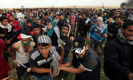 A wounded Palestinian woman is evacuated during clashes with Israeli troops, during a tent city protest along the Israel border with Gaza, demanding the right to return to their homeland, the southern Gaza Strip March 30, 2018. REUTERS/Ibraheem Abu Mustafa