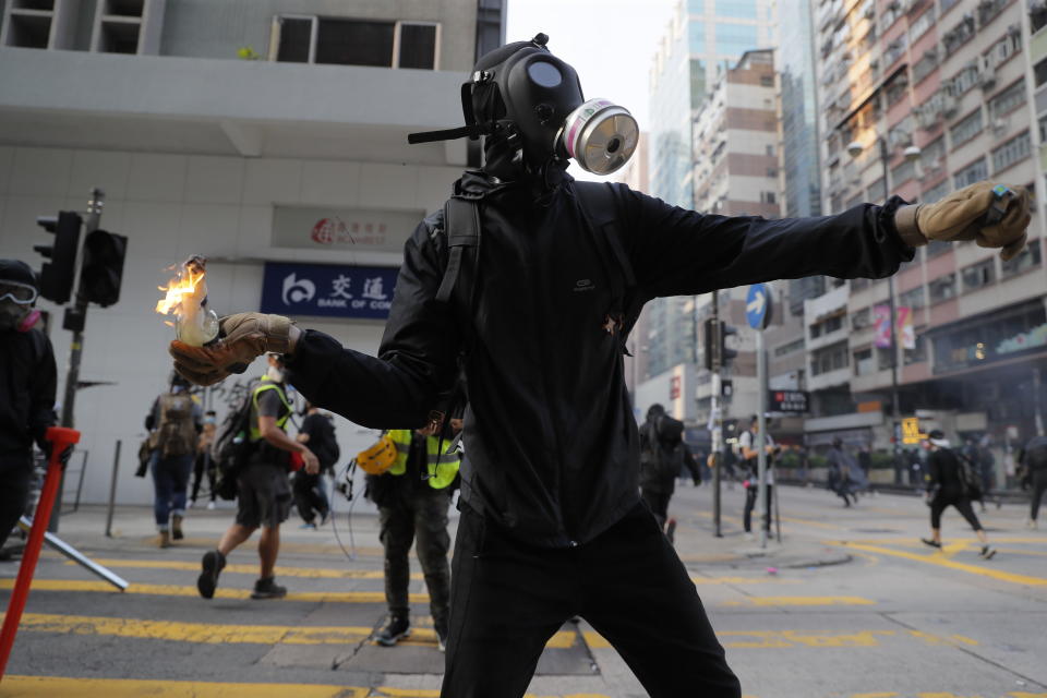 A protester prepares to throw a Molotov cocktail at a police station in Hong Kong, Sunday, Oct. 20, 2019. Hong Kong protesters again flooded streets on Sunday, ignoring a police ban on the rally and demanding the government meet their demands for accountability and political rights. (AP Photo/Kin Cheung)