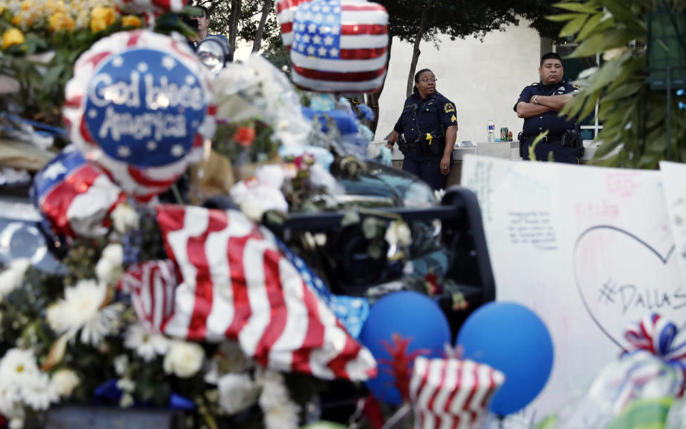 Dallas police officers keep watch over a makeshift memorial at the police headquarters