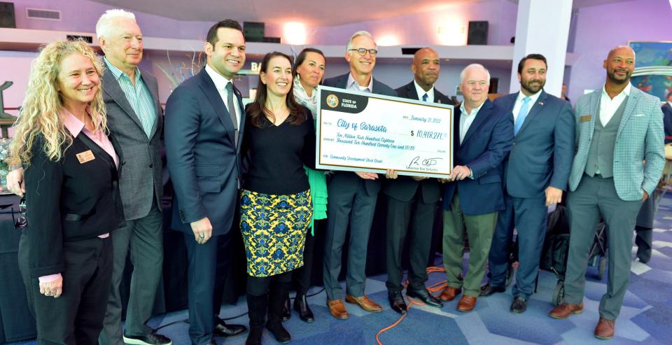 Sarasota city officials and staff from The Bay Sarasota project pose for a photo with a ceremonial check following a press conference at the Van Wezel Performing Arts Hall.