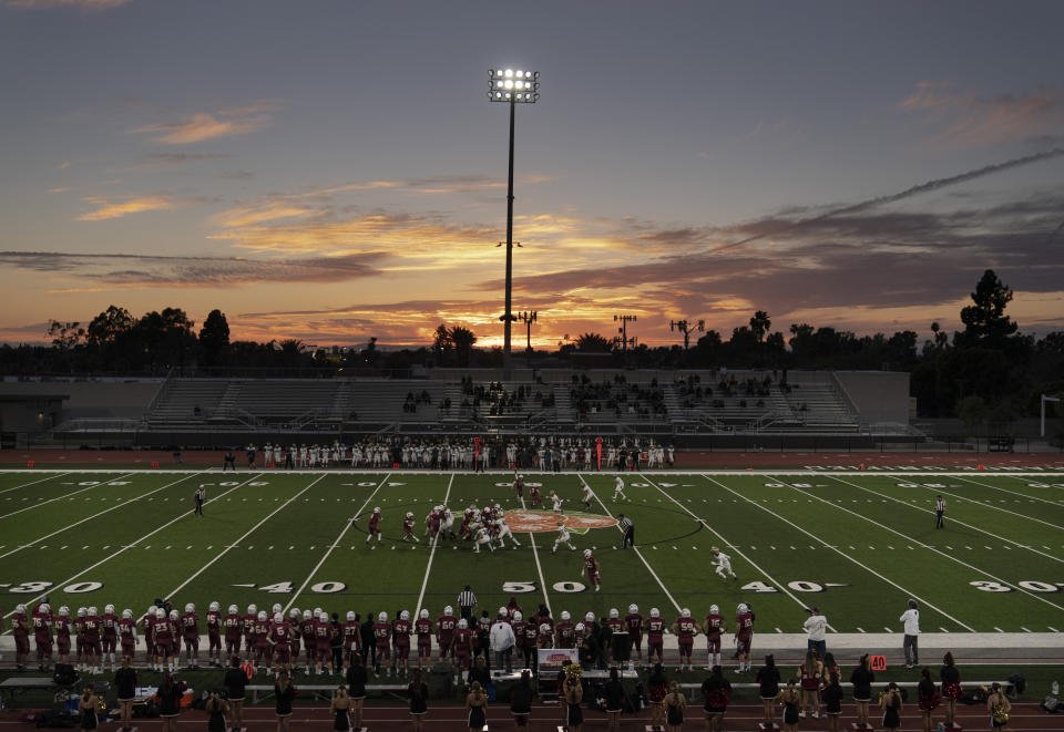 The sun sets behind the stadium during a high school football game between El Modena and El Dorado in Orange, Calif., Friday, March 19, 2021. The team recently played its first football game in a year as more California counties ease coronavirus restrictions and life in the nation’s most populous state inches back to normalcy. (AP Photo/Jae C. Hong)