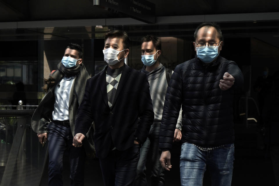 Image: People wearing masks walk in Central, a business district in Hong Kong