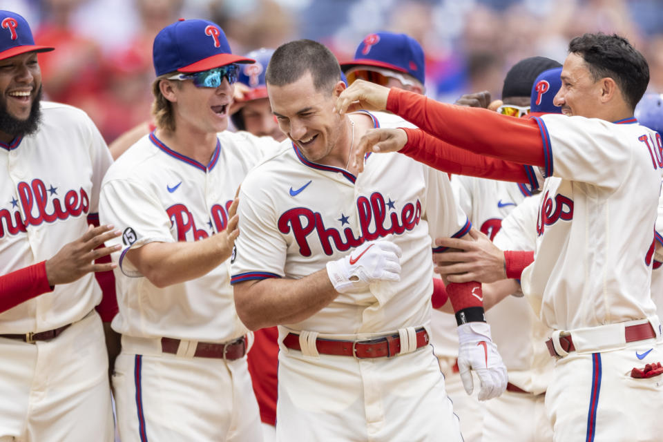 Philadelphia Phillies' J.T. Realmuto, center, is congratulated after hitting the winning home run in the 10th inning of a baseball game against the Miami Marlins, Sunday, July 18, 2021, in Philadelphia. It was a continuation of the previous day's game which was suspended due to rain. (AP Photo/Laurence Kesterson)