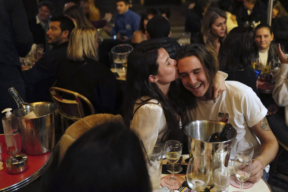 A couple kiss during a drink on the terrace of a restaurant before the nightly curfew due to the restrictions against the spread of coronavirus, in Paris, France, Friday, Oct. 23, 2020. In much of Europe, city squares and streets, be they wide, elegant boulevards like in Paris or cobblestoned alleys in Rome, serve as animated evening extensions of drawing rooms and living rooms. As Coronavirus restrictions once again put limitations on how we live and socialize, AP photographers across Europe delivered a snapshot of how Friday evening, the gateway to the weekend, looks and feels. (AP Photo/Francois Mori)