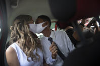 Wearing masks to prevent the spread of the new coronavirus, Thiago do Nascimento, right, and Keilla de Almeida kiss during their drive-thru wedding at the registry office in the neighborhood of Santa Cruz, Rio de Janeiro, Brazil, Thursday, May 28, 2020. Couples have begun turning to this unconventional union at a notary in Santa Cruz since the COVID-19 started battering Brazil. (AP Photo/Silvia Izquierdo)