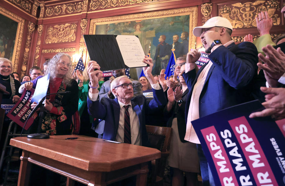 Wisconsin Gov. Tony Evers raises a bill which re-defines the state's legislative maps after signing it at the Wisconsin State Capitol in Madison, Wis., on Monday, Feb. 19, 2024. Democrats tried unsuccessfully for more than a decade to overturn the Republican-drawn maps. But it wasn’t until control of the state Supreme Court flipped in August after the election of liberal Justice Janet Protasiewicz that Democrats found a winning formula. (John Hart/Wisconsin State Journal via AP)