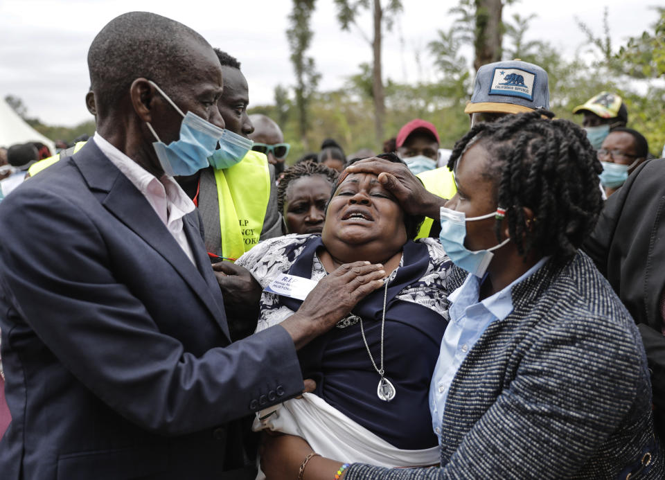 A relative cries as mourners prepare to bury coronavirus victim 27 year old Nancy Ndanu Musyoka, with her daughter Jaylla Musyoka, in Kakungu village, Kitui county, Kenya, Wednesday, July 28, 2021. Nancy, a high school teacher started feeling unwell and was taken to Kitui referral hospital with breathing complications. (AP Photo/Brian Inganga)